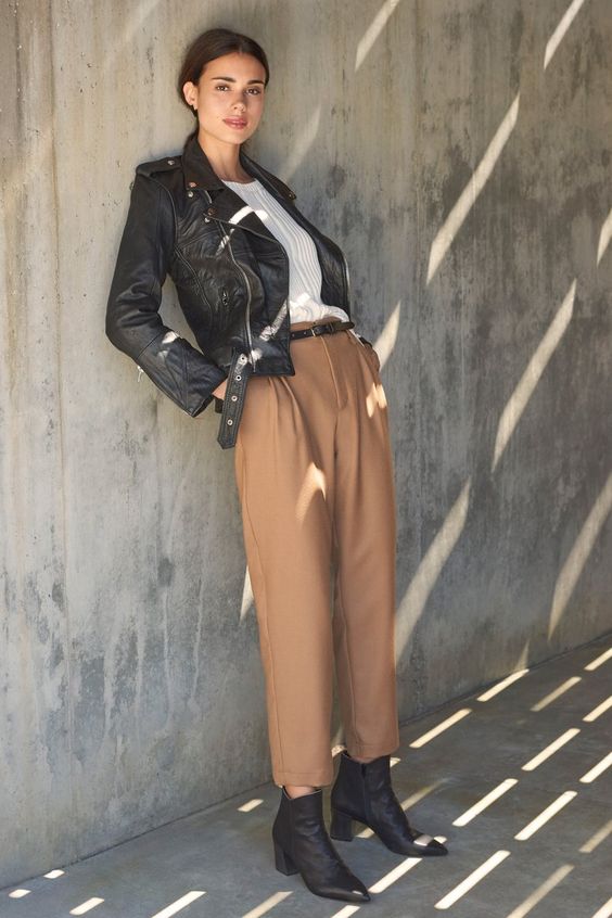 Fall 2020 fashion | posed casual look with black lather jacket, boots and belted tan ankle length trousers